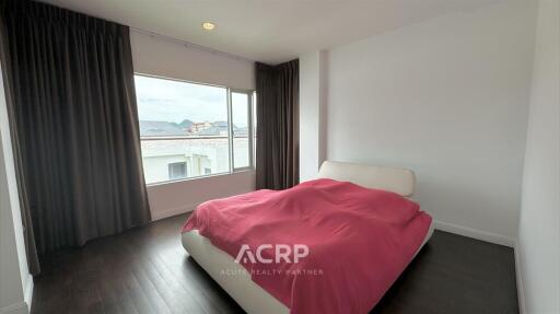 Spacious bedroom with a large window and dark curtains