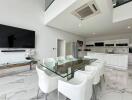 Modern kitchen and dining area with glass table, white chairs, TV, and appliances