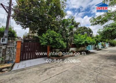 Exterior view of a property with a gate and lush greenery