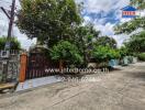 Exterior view of a property with a gate and lush greenery