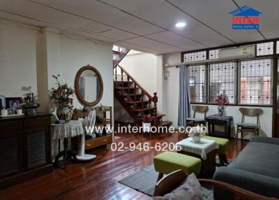 Living room with wooden flooring, decorative items, and a staircase