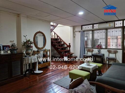 Living room with wooden flooring, decorative items, and a staircase