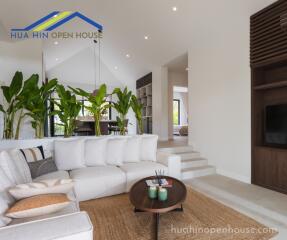 Modern living room with white sofa, indoor plants, and wooden coffee table