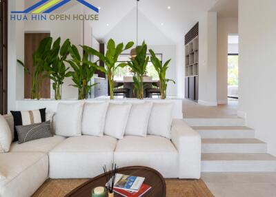 Modern living room with white sofa, indoor plants, and view into dining area