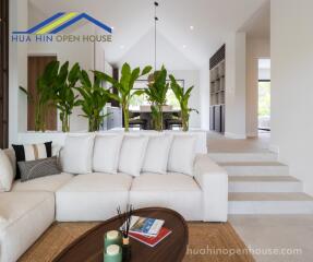 Modern living room with white sofa, indoor plants, and view into dining area