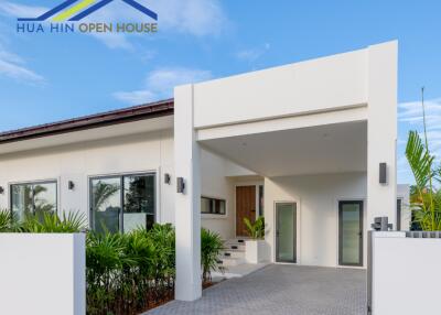 Modern facade of a white single-story house with driveway and greenery