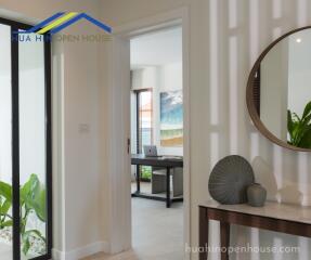 View of a hallway with a small console table and a doorway leading to another room