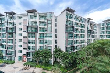 Exterior view of modern apartment complex with balconies and green surrounding