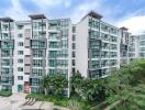 Exterior view of modern apartment complex with balconies and green surrounding