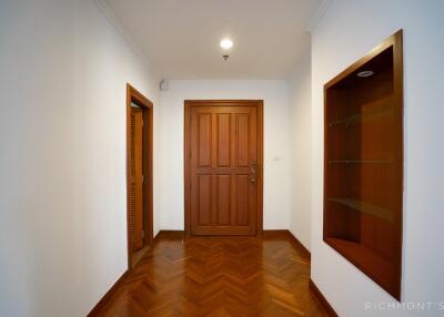 Wooden door in a white-painted hallway with a small display niche