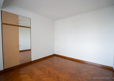 A minimalistic bedroom with wooden parquet flooring and wall-mounted storage