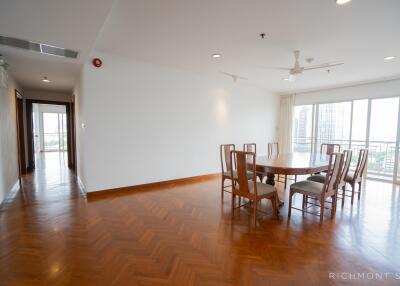 Spacious dining area in an open floor plan with wooden flooring and large windows