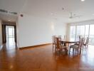 Spacious dining area in an open floor plan with wooden flooring and large windows