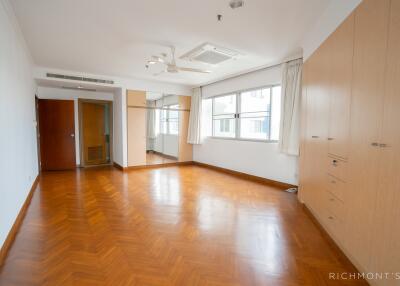 Spacious bedroom with wooden flooring and large windows