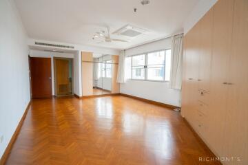 Spacious bedroom with wooden flooring and large windows