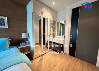 Bedroom with modern furnishing and built-in wardrobe, featuring wooden floors and a vanity area.