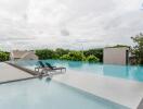 Infinity pool with deck chairs and greenery