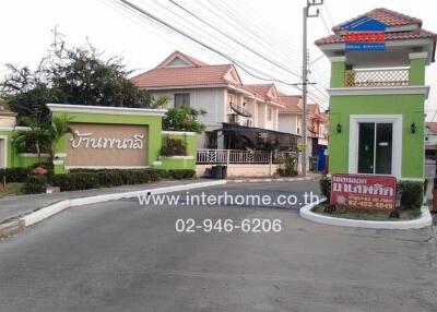 Entrance to residential complex with security booth and house