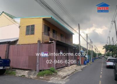 Two-story residential building with wooden exterior, located on a side street with nearby parked vehicles.