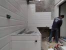 Modern kitchen under renovation with white wall tiles and a worker