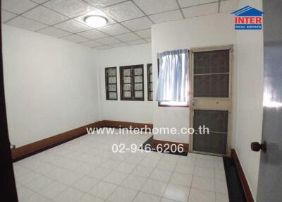 Vacant room with tiled floor, metal door, and windows with security bars