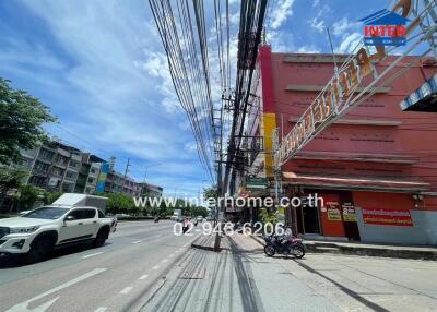 Street view of a commercial building with cars and a motorbike