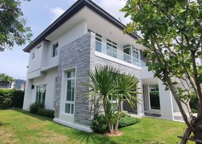 Modern two-story house exterior with garden and trees