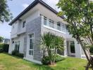 Modern two-story house exterior with garden and trees