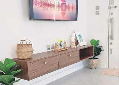 Modern living room with wall-mounted TV and floating wooden shelf