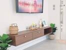 Modern living room with wall-mounted TV and floating wooden shelf