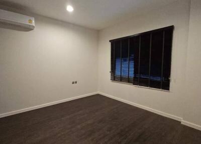 Empty bedroom with wooden floor, air conditioning, and window with blinds