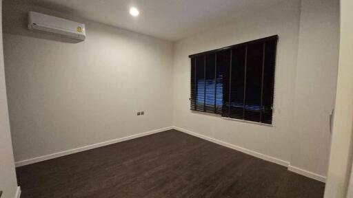 Empty bedroom with wooden floor, air conditioning, and window with blinds