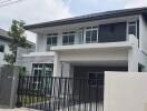 Front view of a modern double-story house with a gated driveway