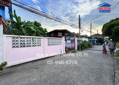 Exterior street view with houses and a pink wall