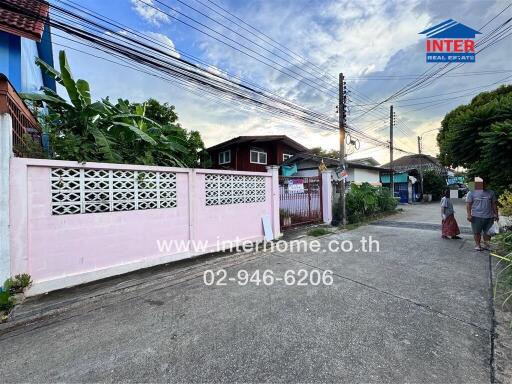 Exterior street view with houses and a pink wall