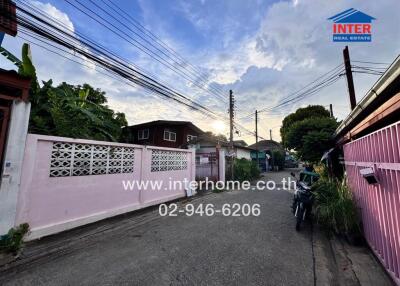 Exterior view of a residential street with buildings, pink fences, and a motorcycle.