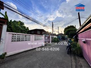 Exterior view of a residential street with buildings, pink fences, and a motorcycle.