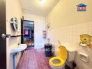 Bathroom with red tile floor, white tiled walls, yellow toilet seat, sink, and mirror