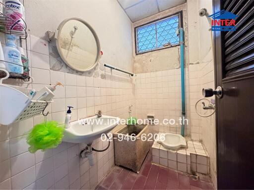 Small bathroom with tile walls, a sink, and a traditional squat toilet