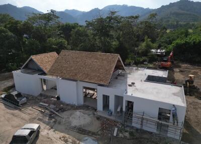 Construction stage of a single-story house with surrounding greenery