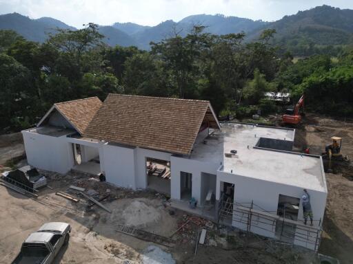 Construction stage of a single-story house with surrounding greenery