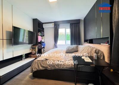 Modern bedroom with large bed, built-in storage, TV, and air conditioning