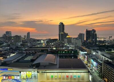 Cityscape view during sunset with tall buildings and ocean in the background