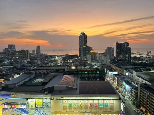 Cityscape view during sunset with tall buildings and ocean in the background