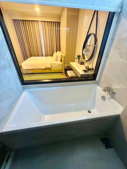 Bathroom with large bathtub and window view to bedroom