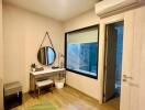 Bedroom with a green rug, mirror, small table, and window overlooking bathroom.