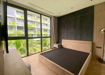 Modern bedroom with large windows and a view of greenery