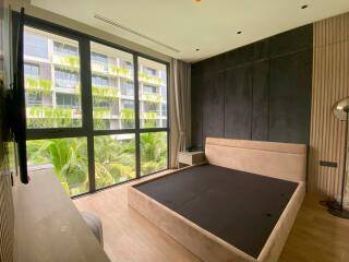 Modern bedroom with large windows and a view of greenery