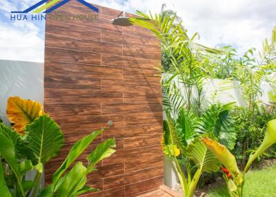 Outdoor shower area with wooden paneling and tropical plants