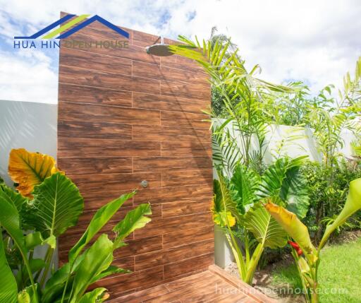 Outdoor shower area with wooden paneling and tropical plants